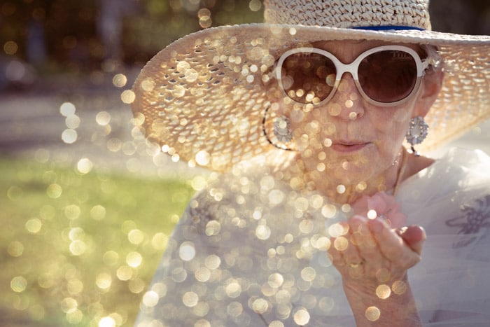 Woman blowing glitter against the sun